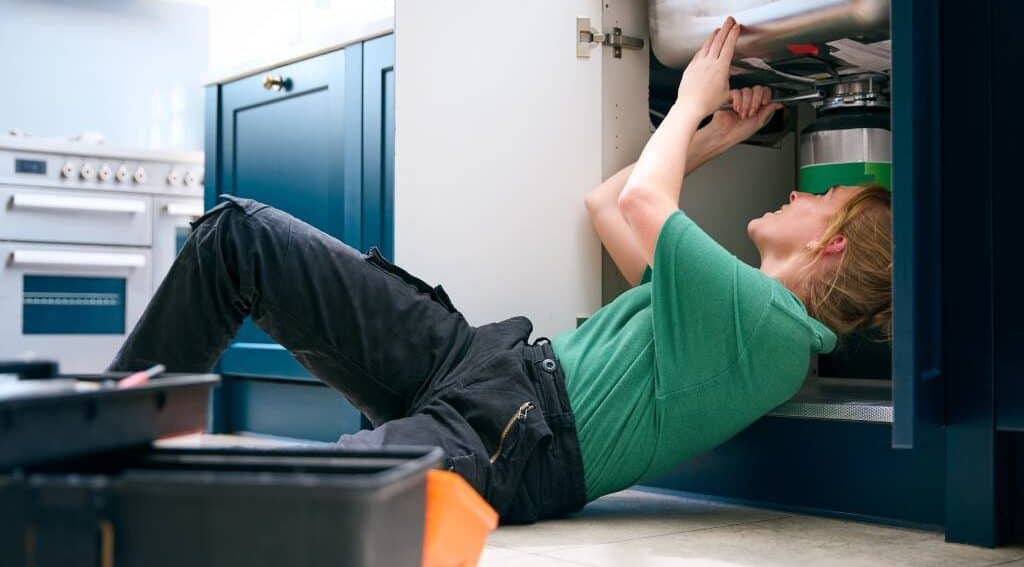 A plumber working under a sink A plumber working under a sink.